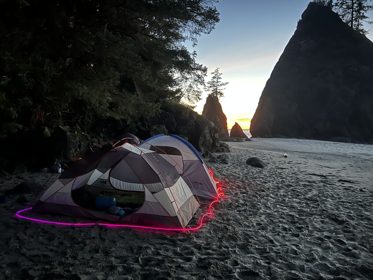 A tent on a beach at sunset outlined in glowing magenta Trippy Wire.